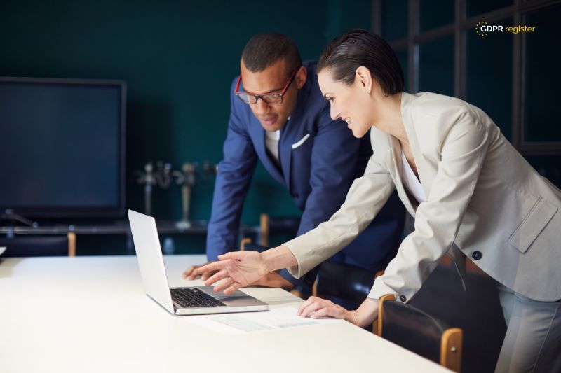 Two professionals collaborating on a laptop, symbolising teamwork in creating a guide to developing a data breach response plan.